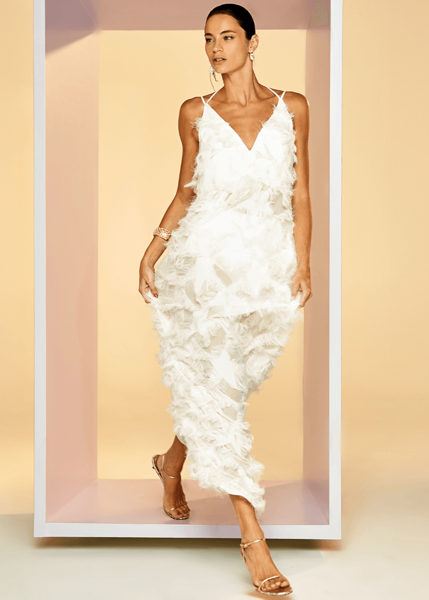 Woman wearing a white floral dress against a beige background