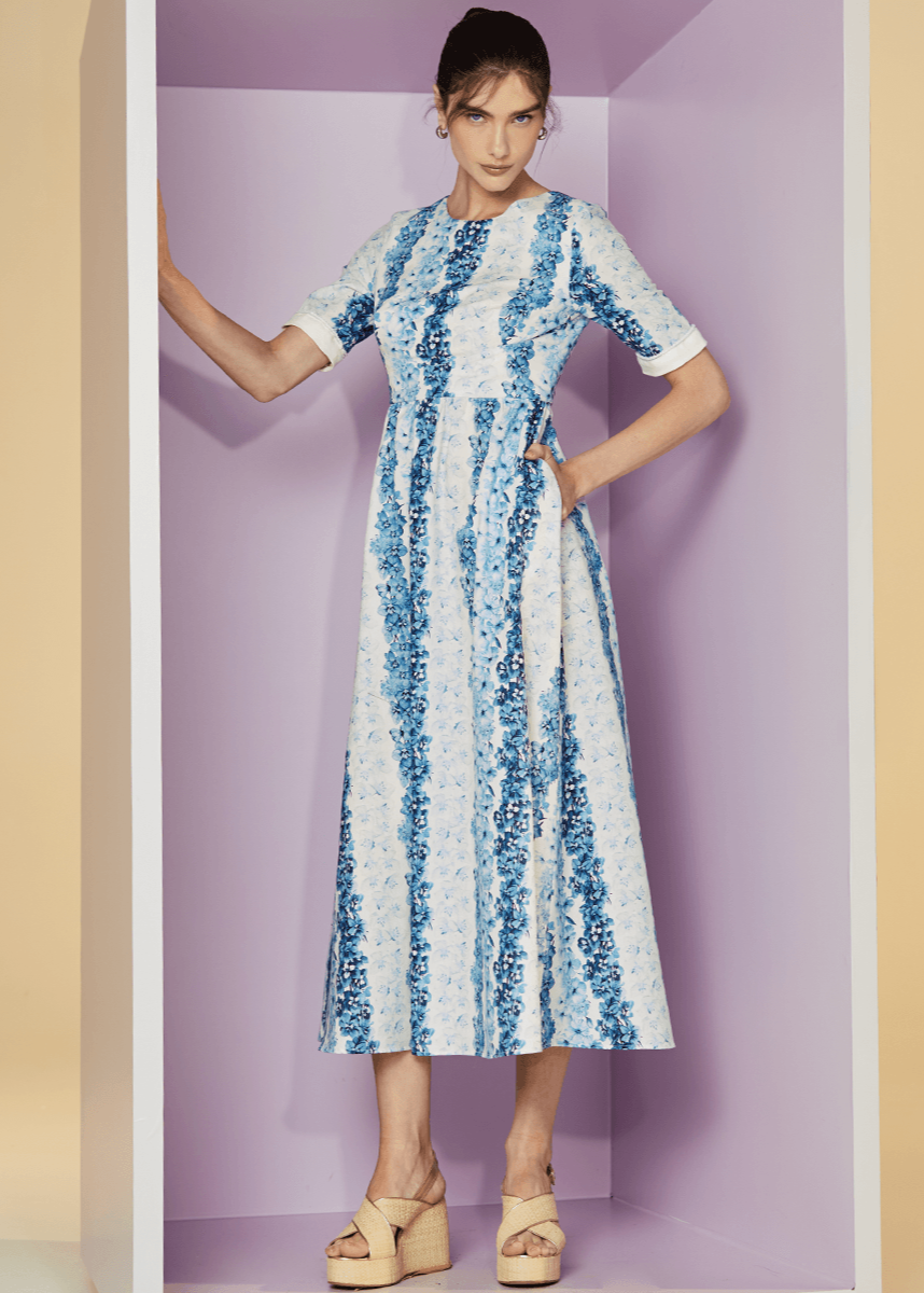 Woman wearing a blue and white patterned dress against a purple background