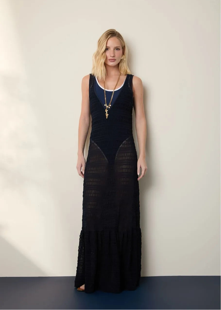 Woman wearing a black dress with sheer panels against a white wall