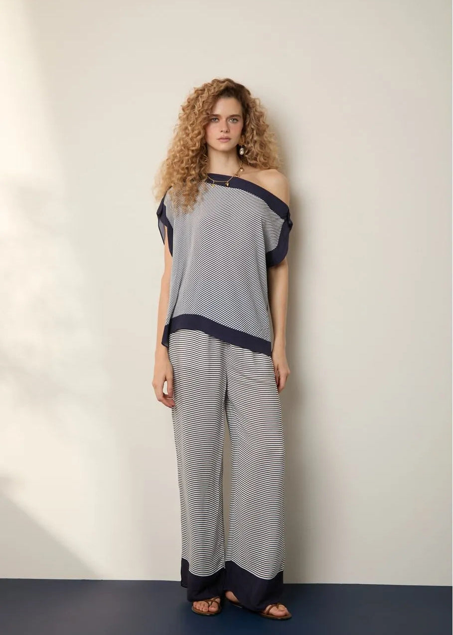 Woman wearing a gray and navy outfit against a plain background