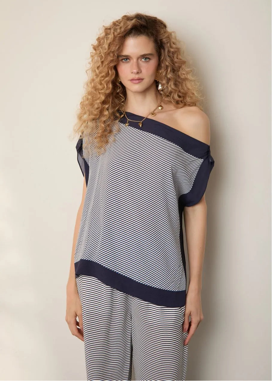 Woman wearing a striped off-shoulder top and pants against a plain background