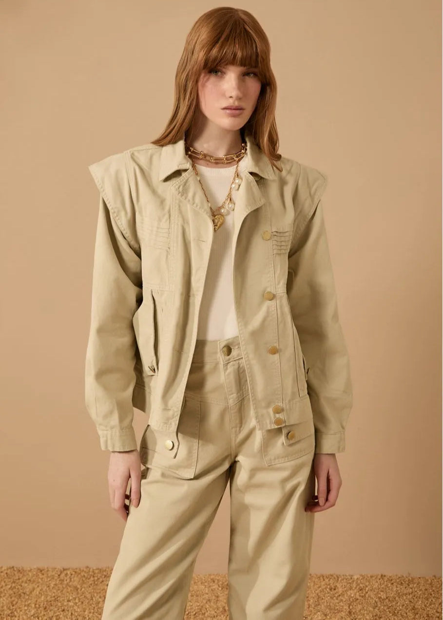 Woman wearing a beige jacket and pants against a beige background