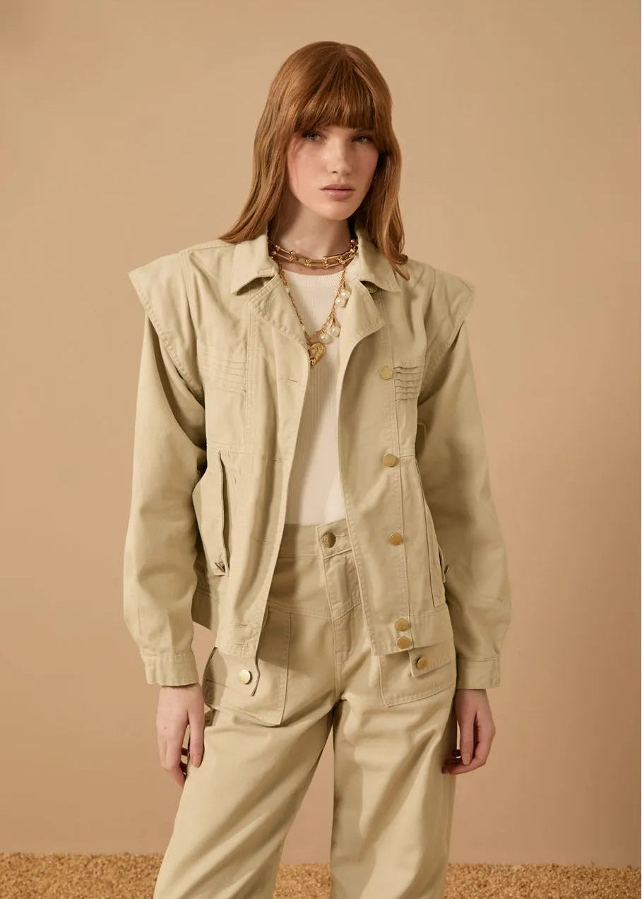 Woman wearing a beige jacket and pants against a beige background