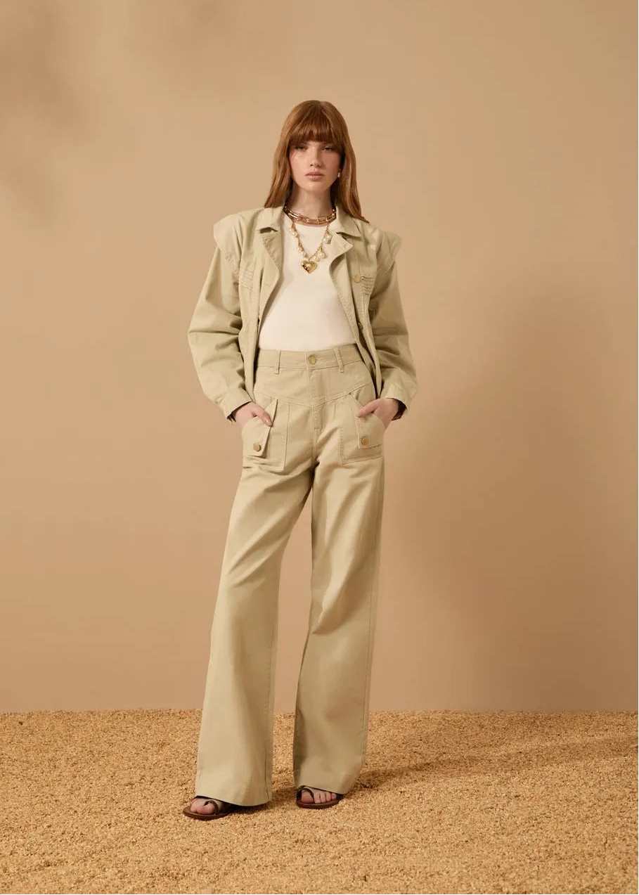 Woman wearing a beige jacket and pants against a beige background