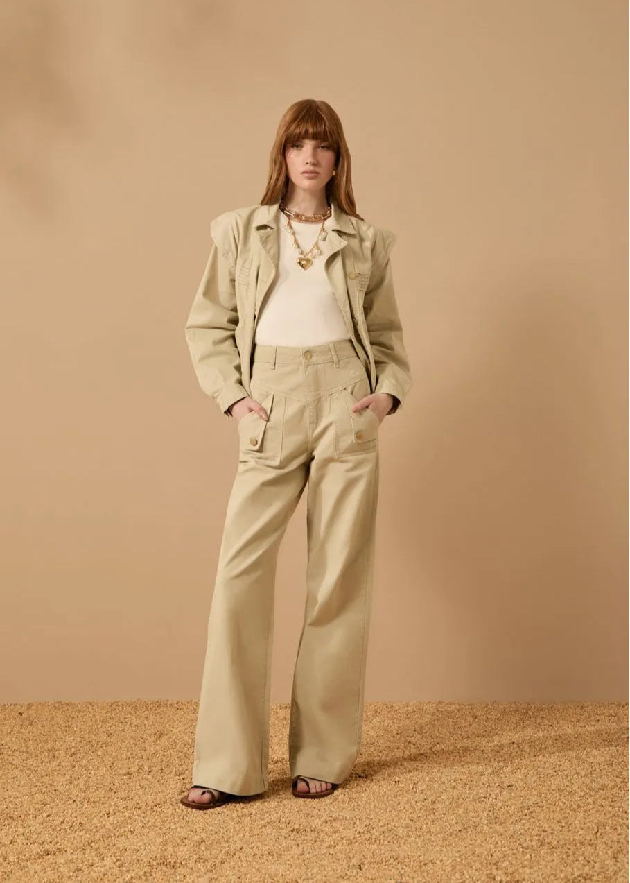 Woman wearing a beige jacket and pants against a beige background