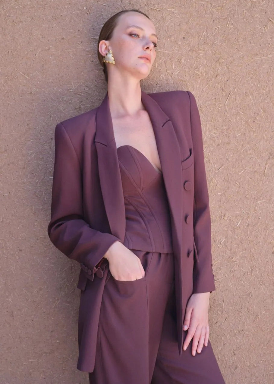 Woman wearing a purple suit against a textured beige wall