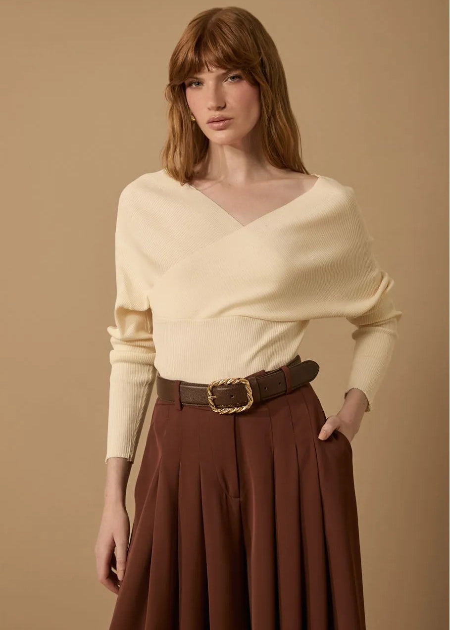 Woman wearing a beige top and brown skirt against a beige background