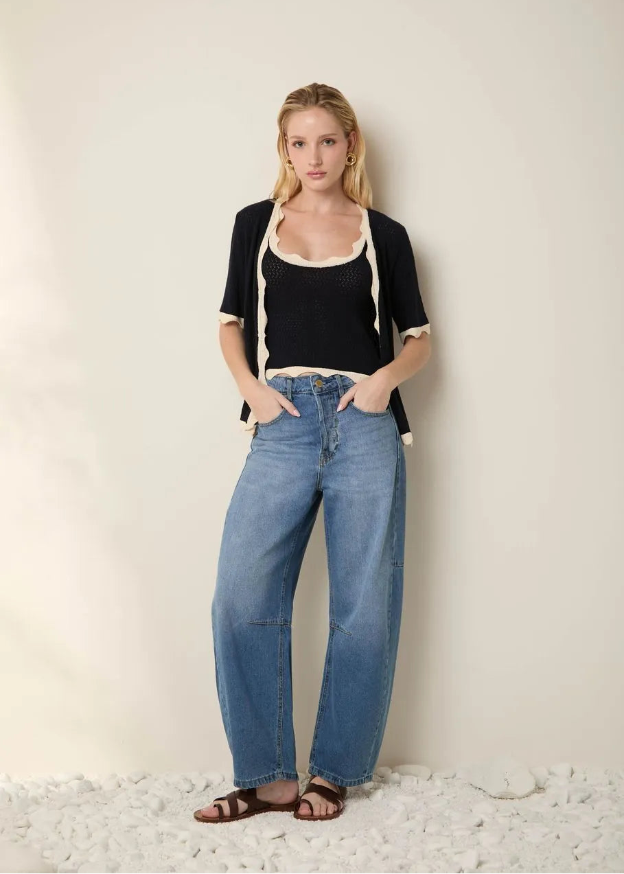 Woman wearing a black top and blue jeans against a plain background