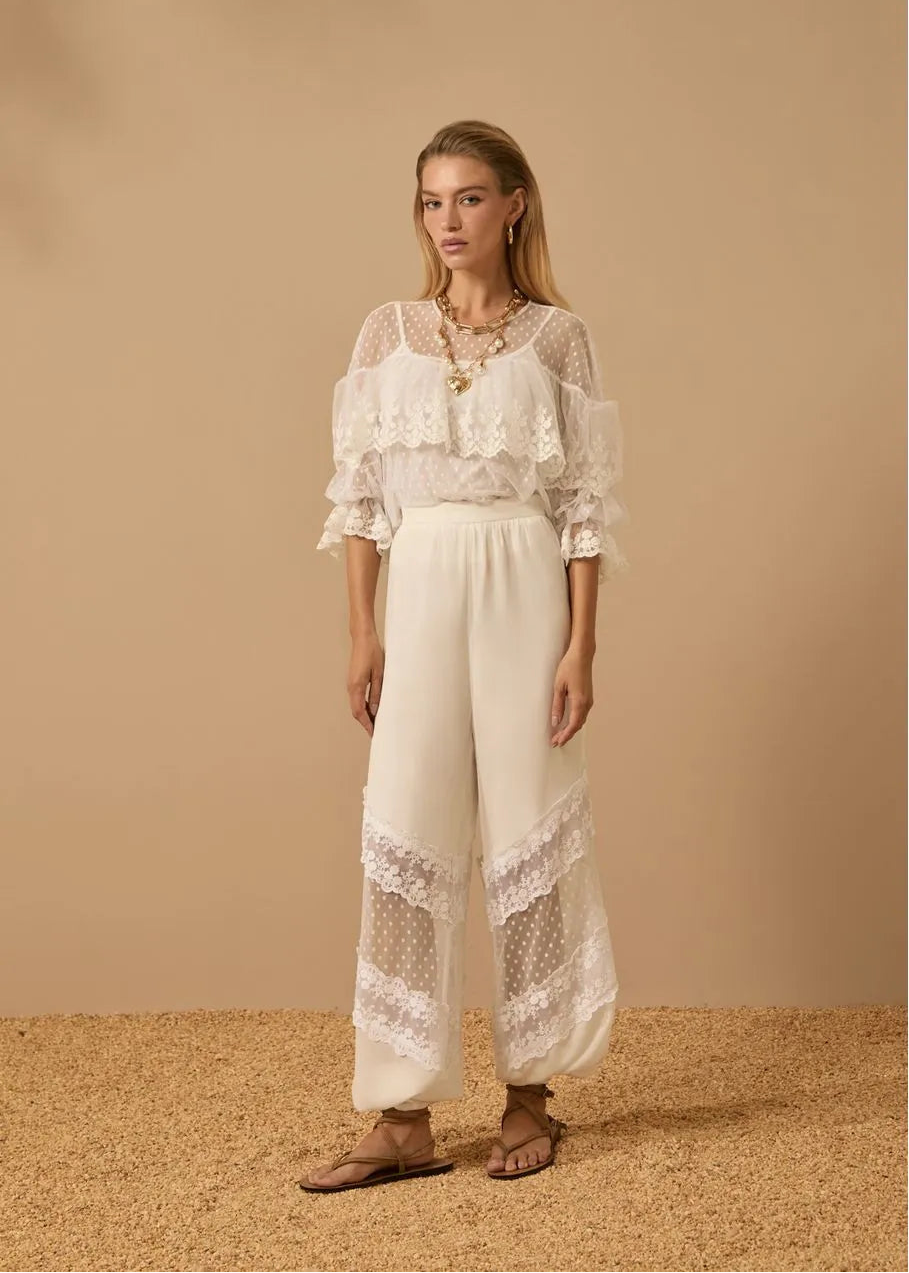 Woman wearing a white lace outfit against a beige background