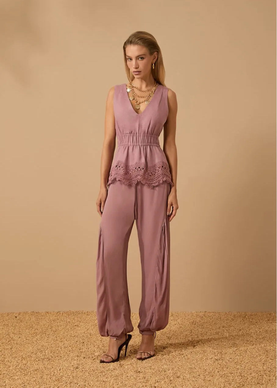 Woman wearing a pink jumpsuit against a beige background