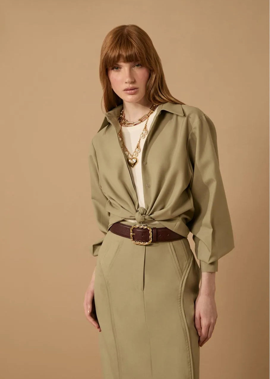 Woman wearing a beige outfit with a belt against a beige background