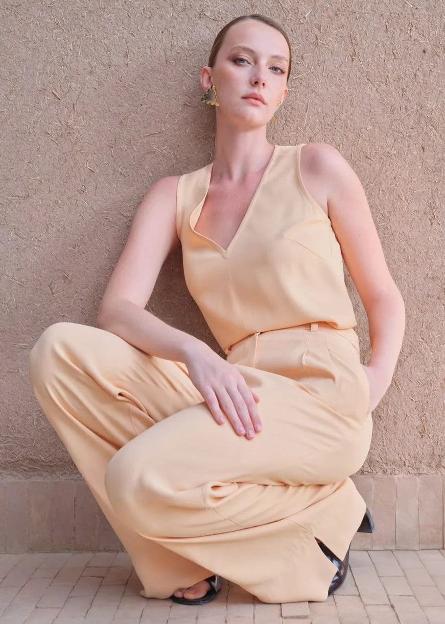 Woman in a yellow dress sitting against a beige wall.