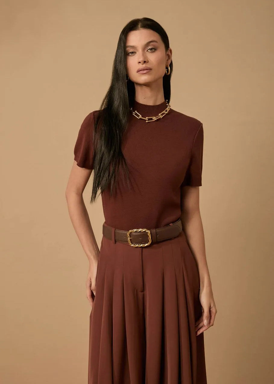 Woman wearing a brown dress with a belt against a beige background
