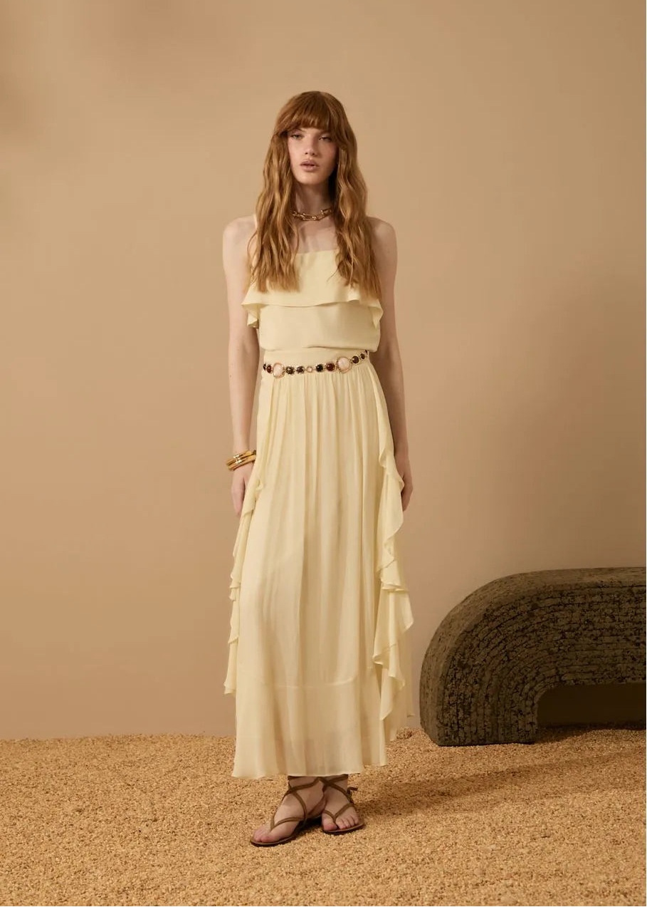 Woman wearing a light yellow dress standing against a beige background