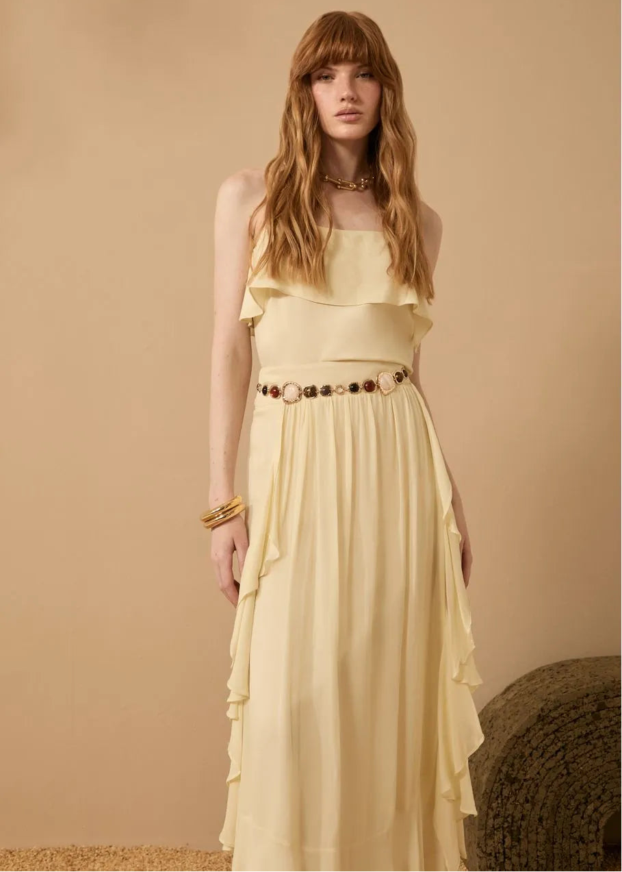 Woman wearing a yellow dress with a belt against a beige background