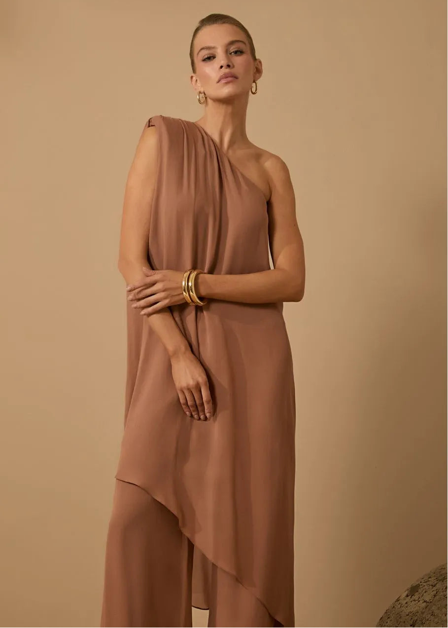 Woman wearing a brown one-shoulder dress against a beige background