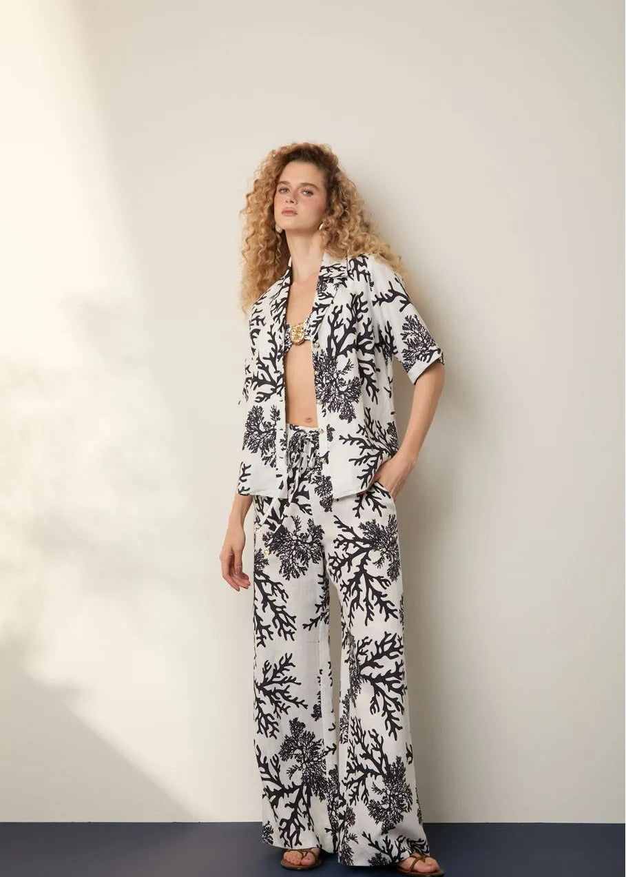 Woman wearing a black and white floral outfit against a plain background