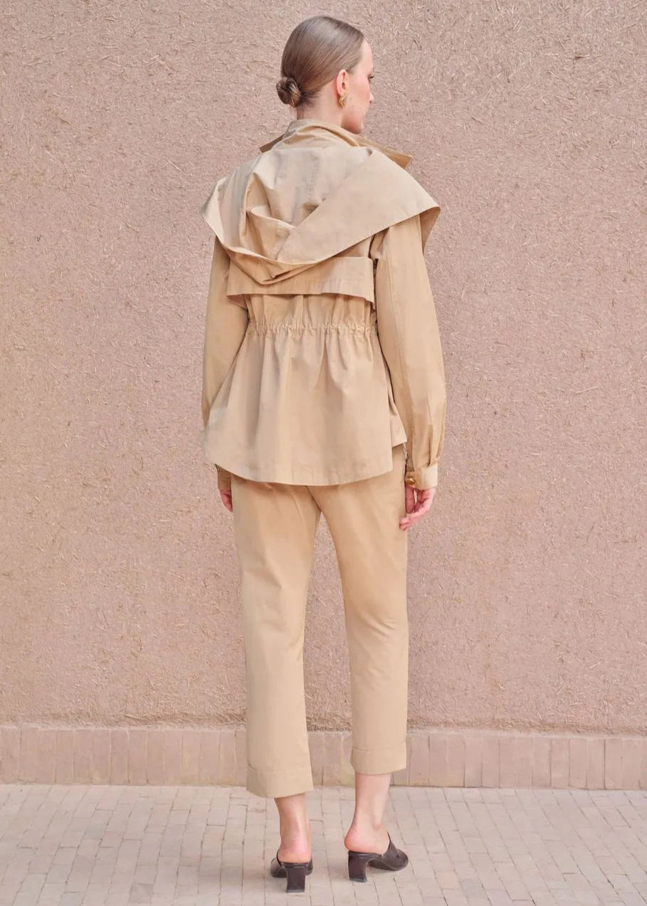 Woman wearing a beige outfit against a pink wall