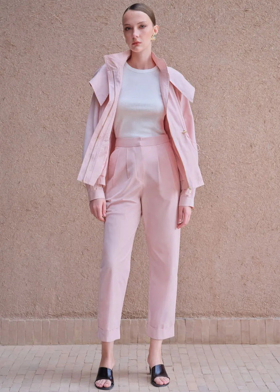 Woman wearing a pink outfit against a beige wall