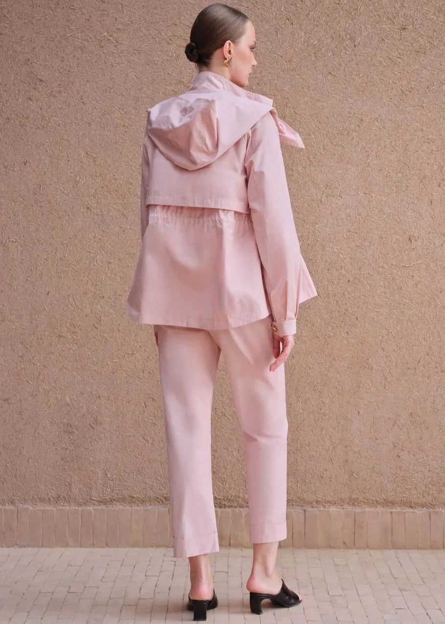 Person wearing a pink outfit standing against a beige wall.