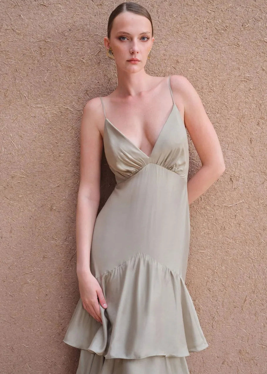 Woman wearing a light green dress against a beige wall