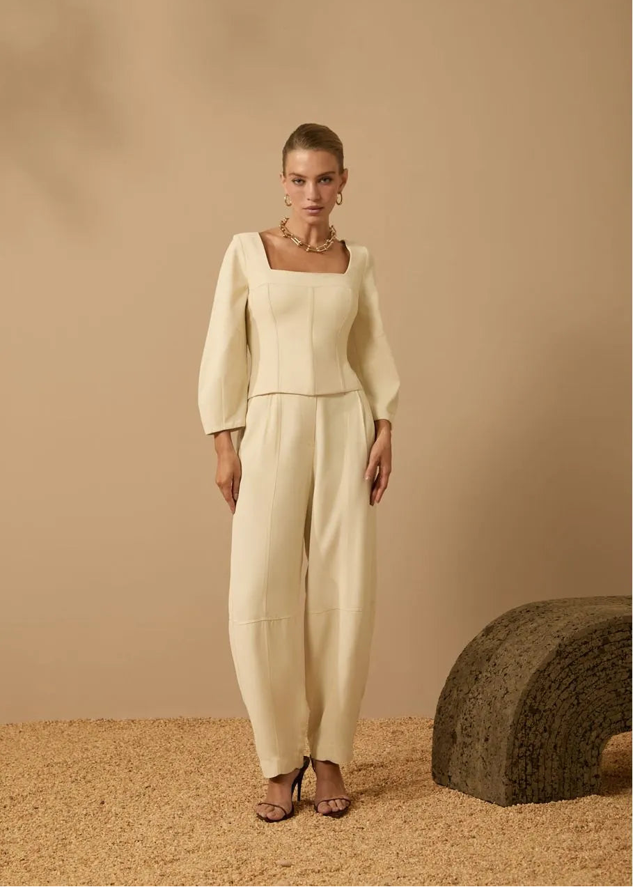 Woman wearing a cream-colored outfit against a beige background