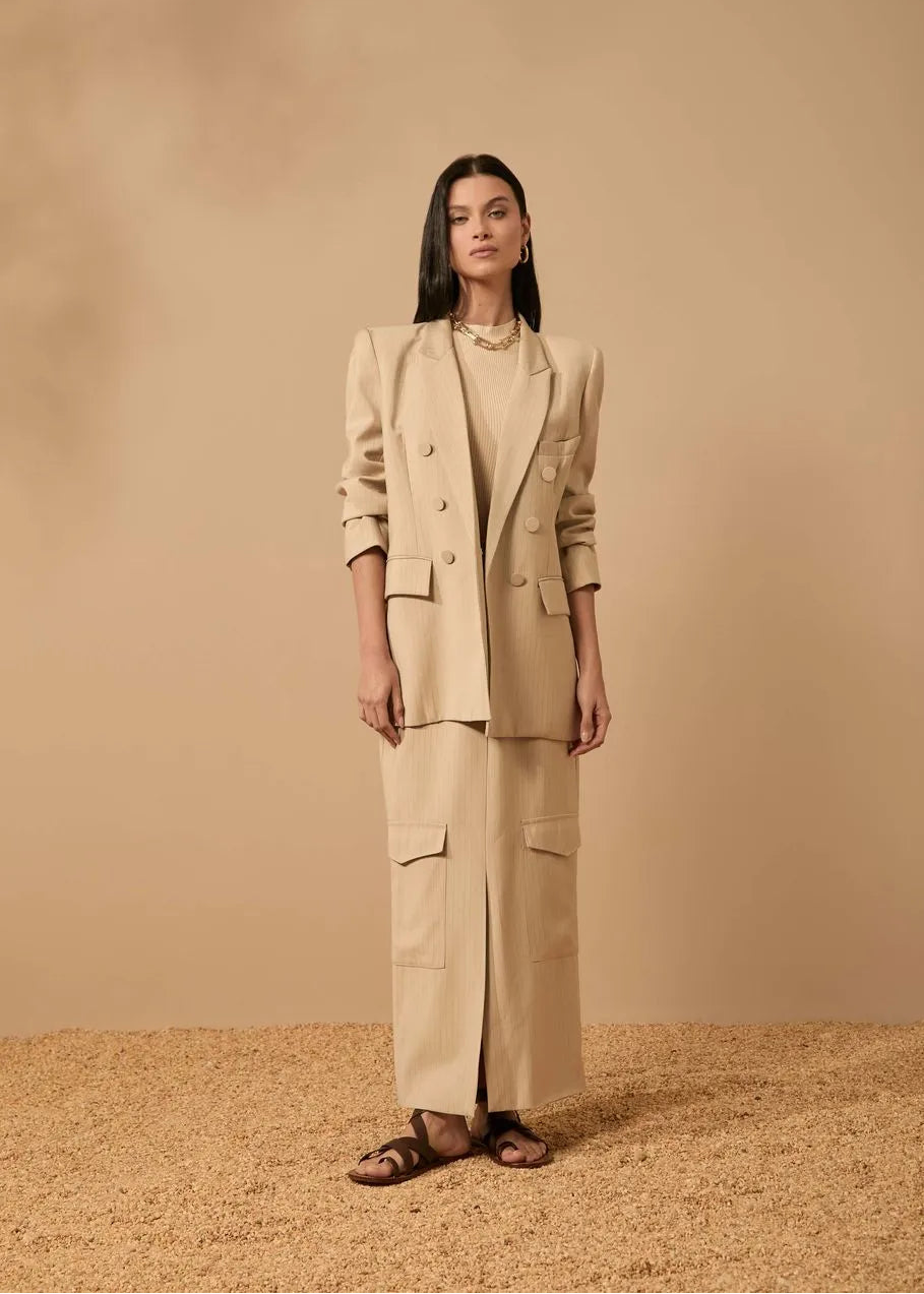 Woman wearing a beige suit standing against a beige background