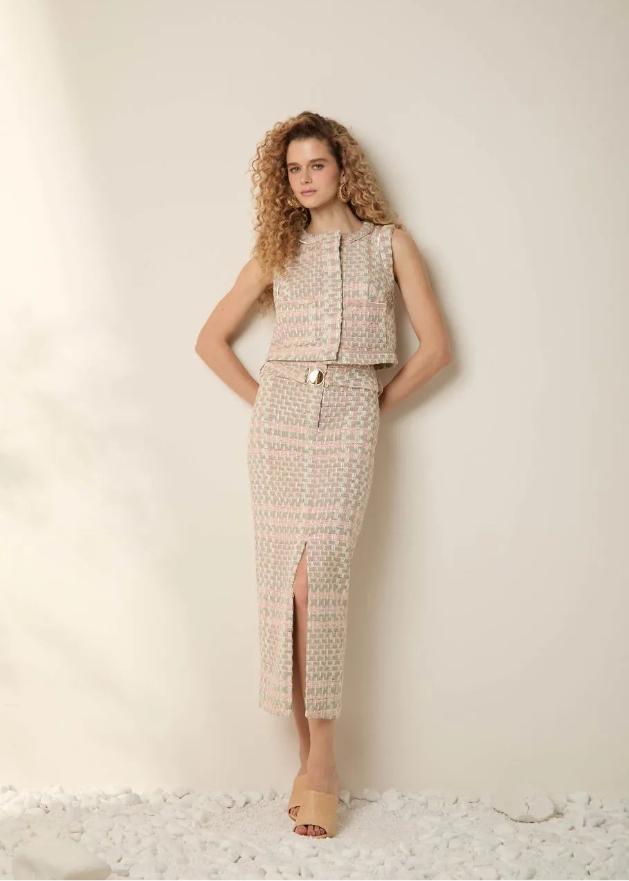 Woman wearing a patterned sleeveless top and high-waisted pants against a plain background