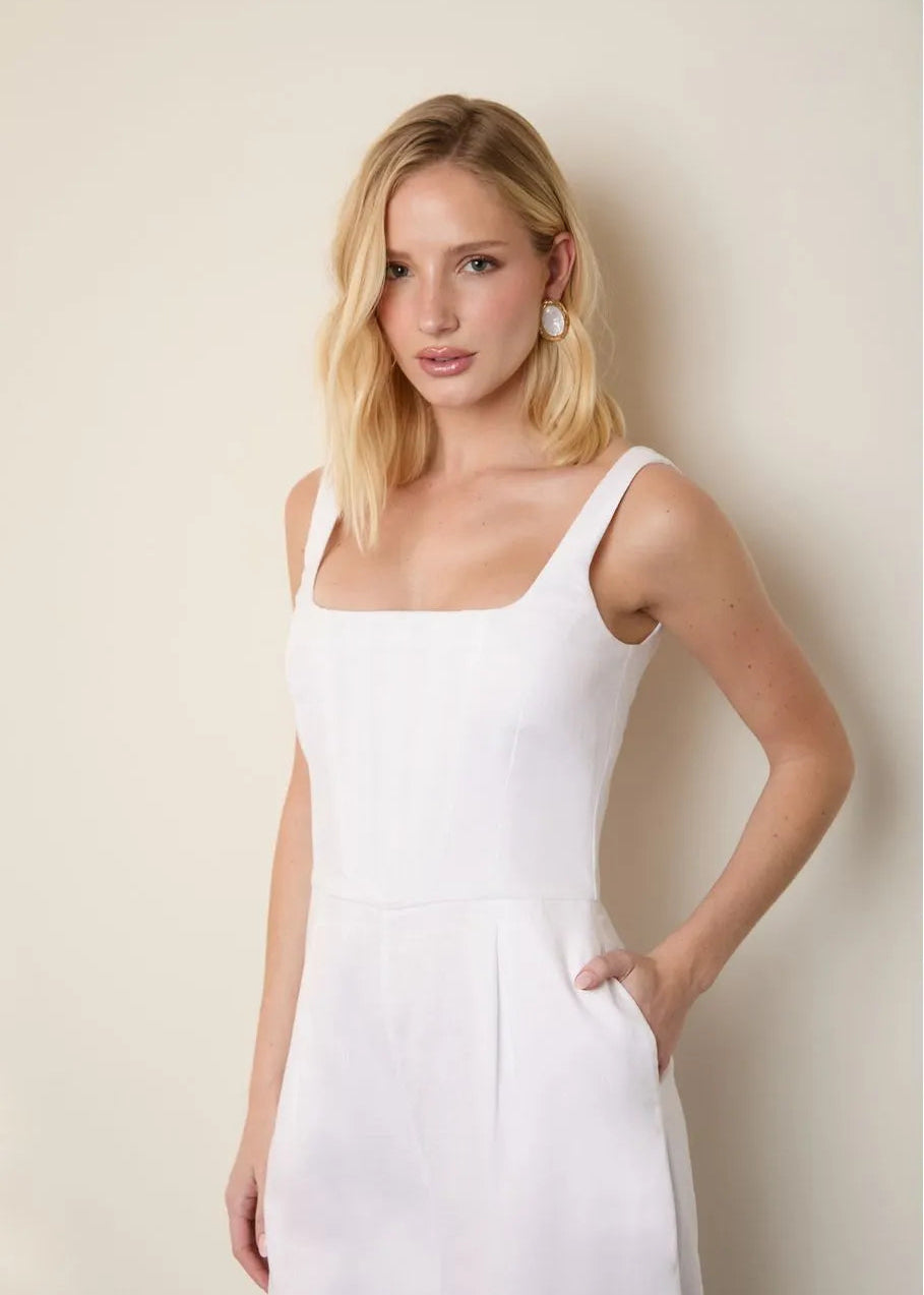 Woman wearing a white sleeveless dress against a plain background