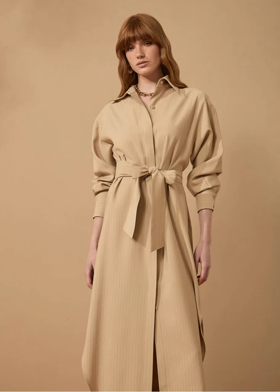 Woman wearing a beige trench coat against a beige background