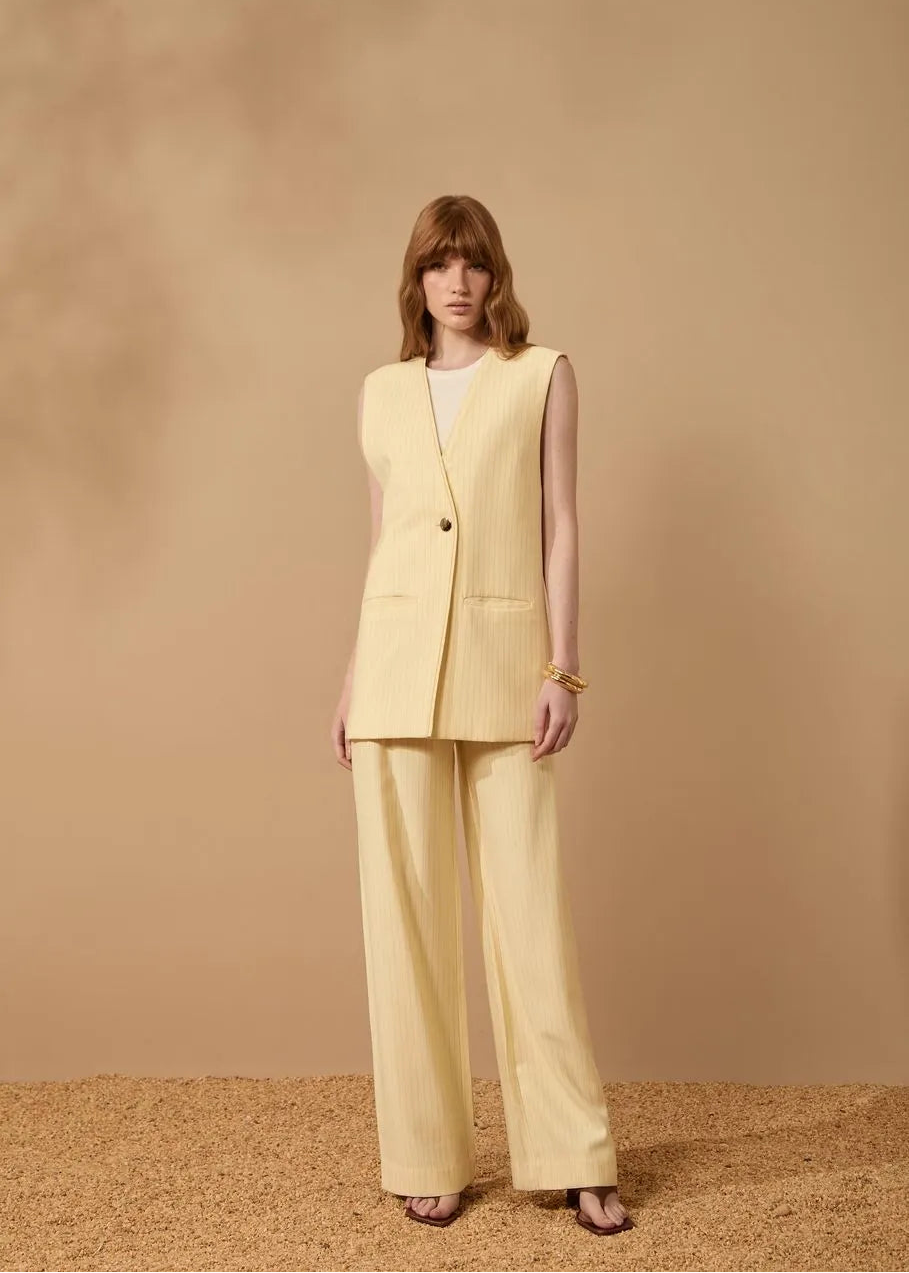 Woman wearing a light yellow suit against a beige background