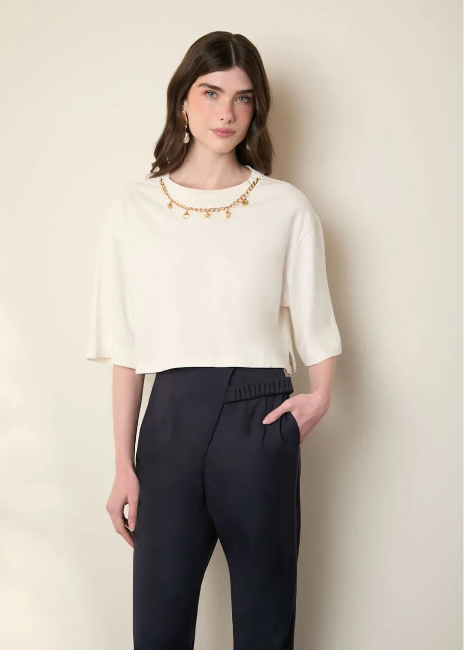 Woman wearing a white blouse and dark pants against a plain background