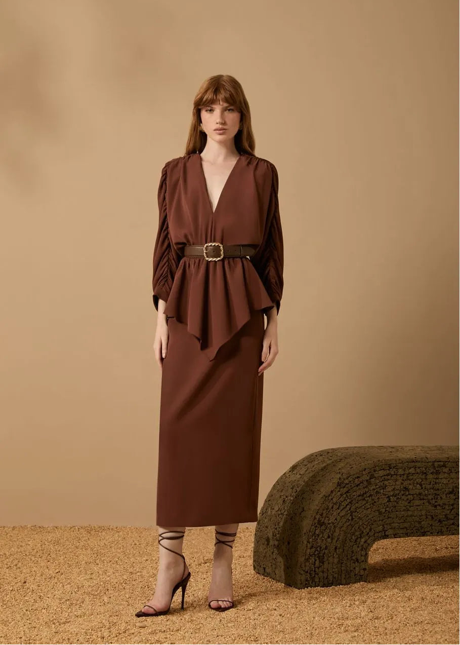Woman wearing a brown dress with a belt against a beige background