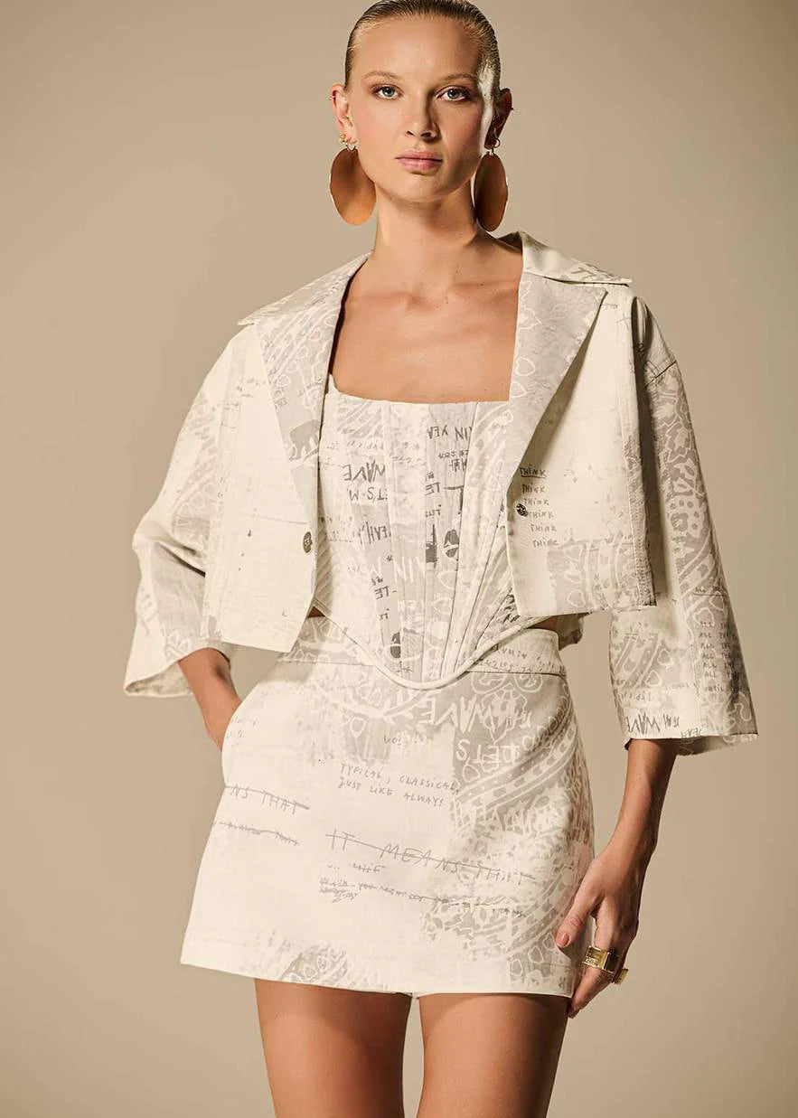 Woman wearing a cream-colored lace dress with matching jacket against a beige background