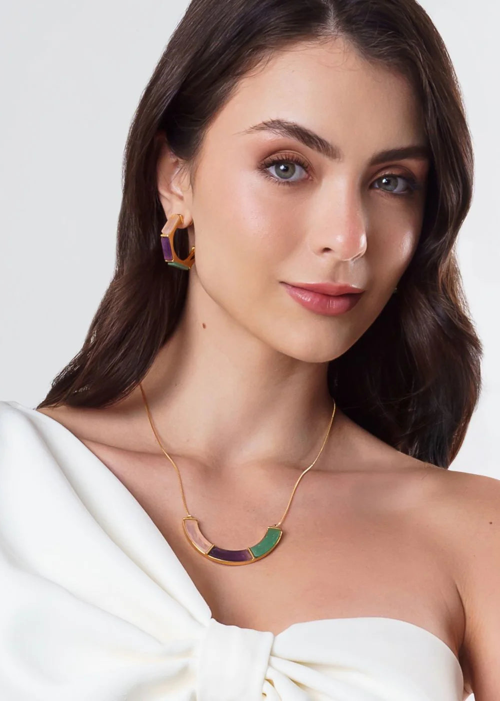 Woman wearing gold necklace and earrings on a white background