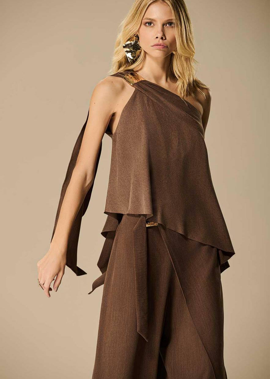 Woman wearing a brown one-shoulder dress against a beige background