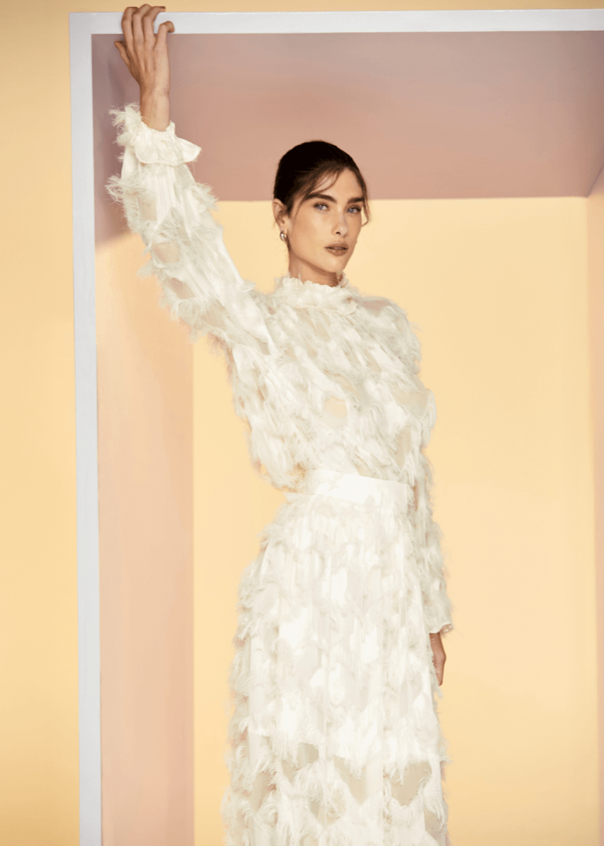 Woman wearing a white floral dress against a plain background