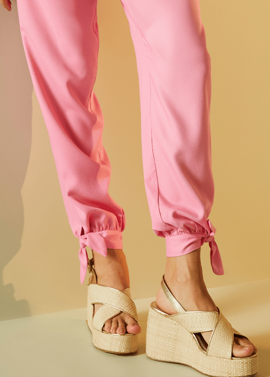 Person wearing pink pants and beige wedge sandals on a beige background