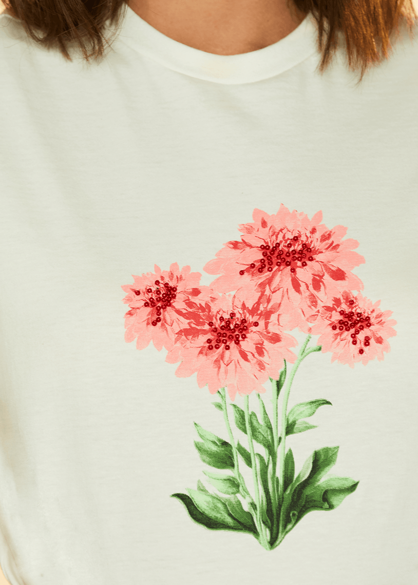 White t-shirt with pink floral design on a plain background