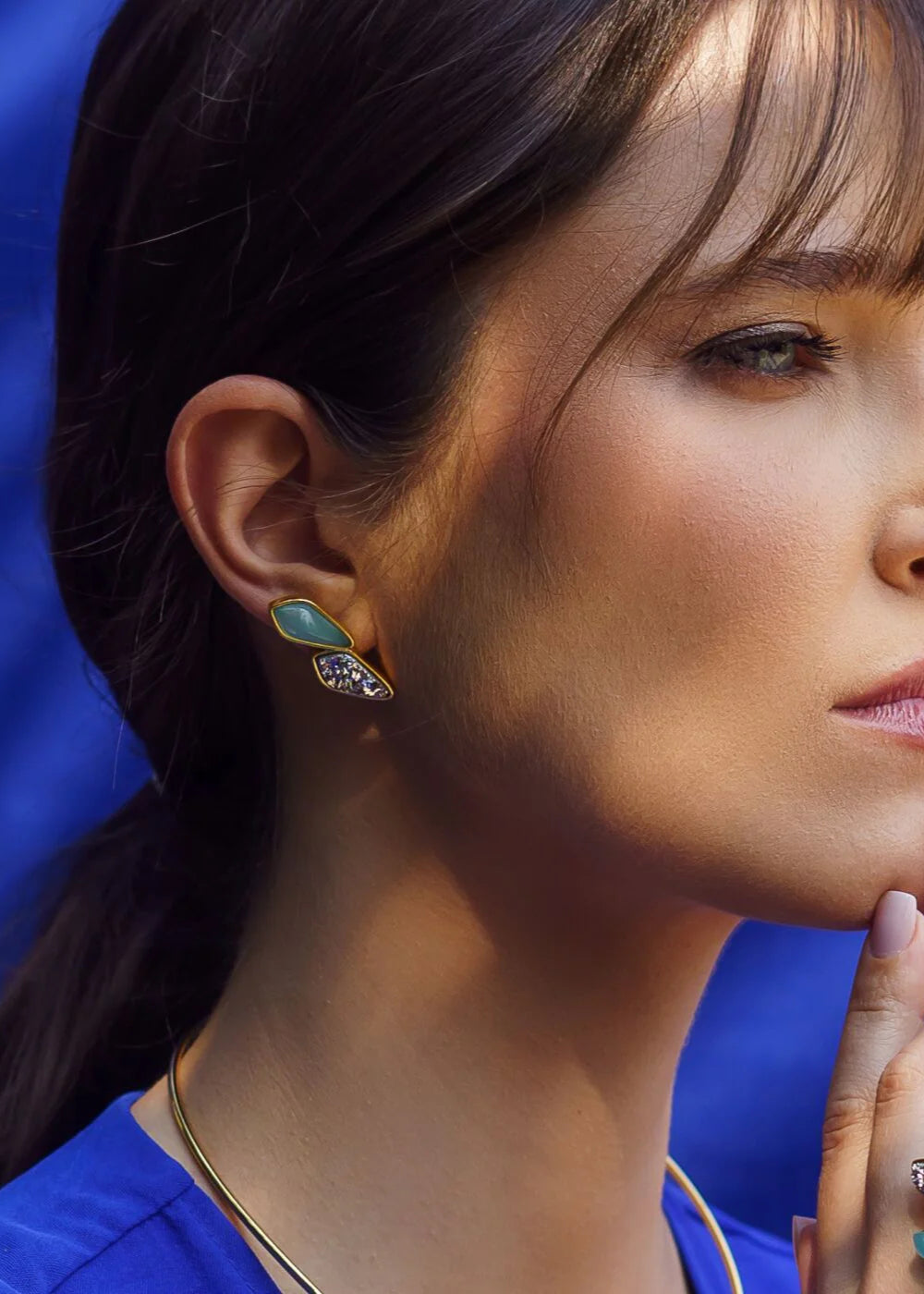 Close-up of a woman wearing earrings with a blue background