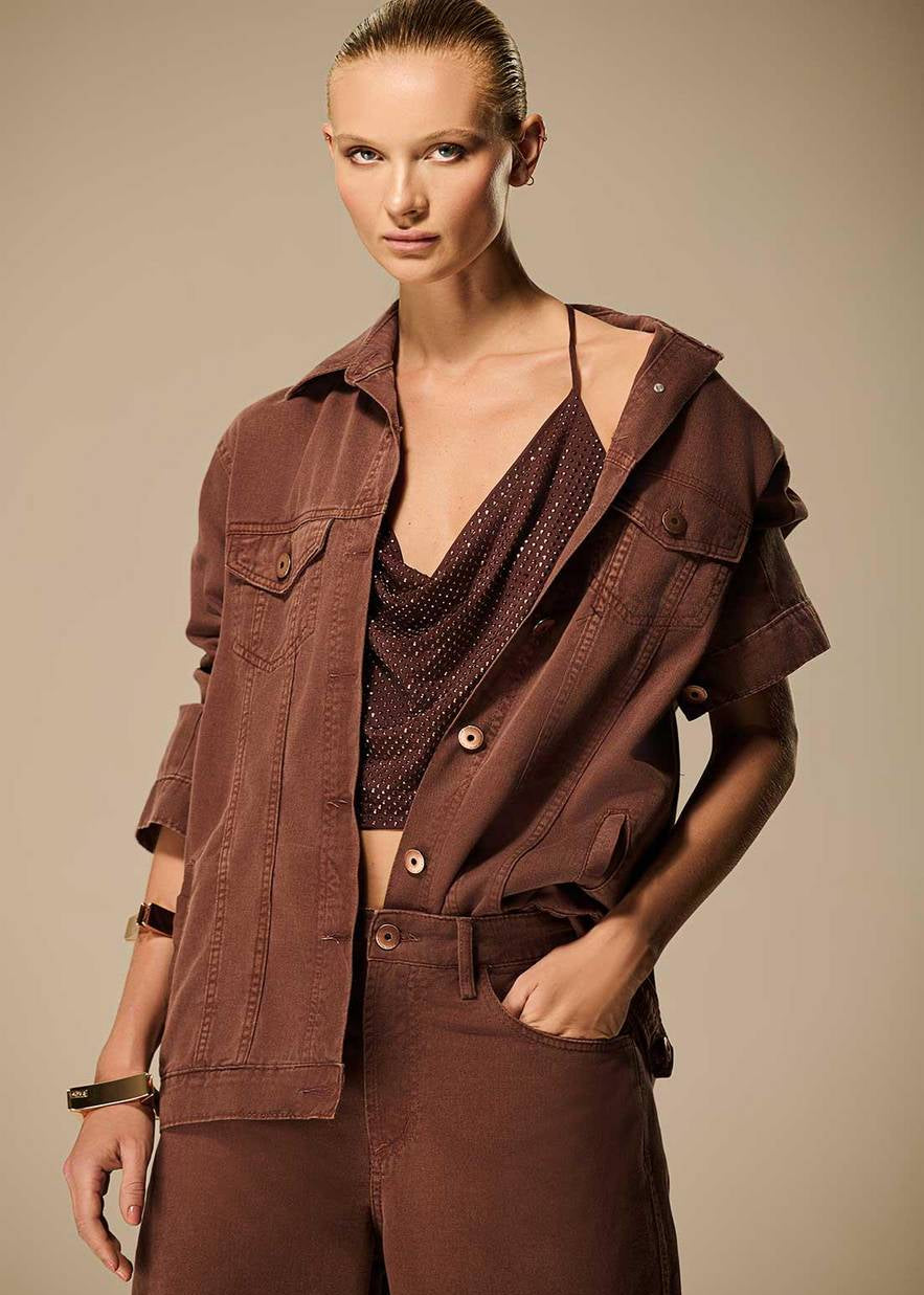 Woman wearing a brown outfit with a jacket and pants on a beige background