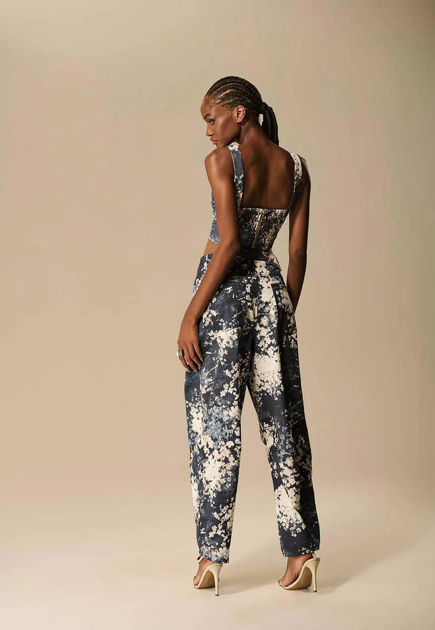 Woman wearing a floral jumpsuit against a beige background