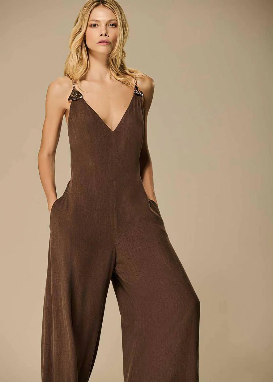 Woman wearing a brown jumpsuit against a beige background