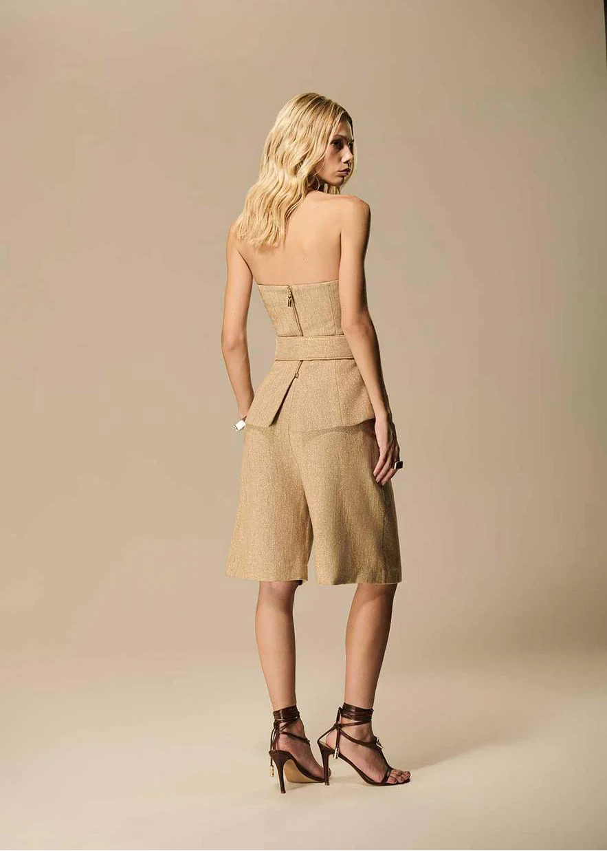 Woman wearing a beige strapless top and shorts set on a beige background