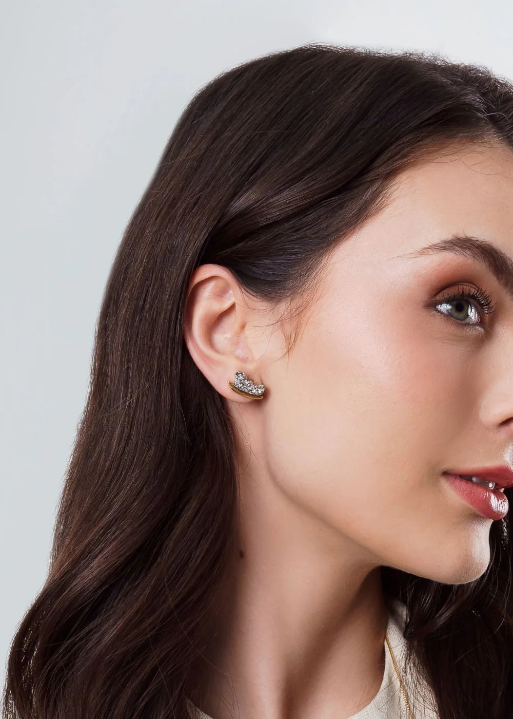 Close-up of a woman wearing earrings with a plain background