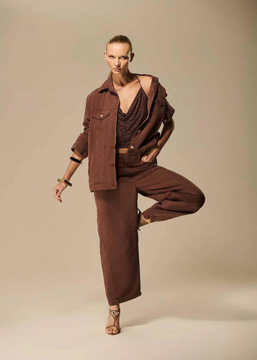 Woman in a brown outfit posing against a beige background