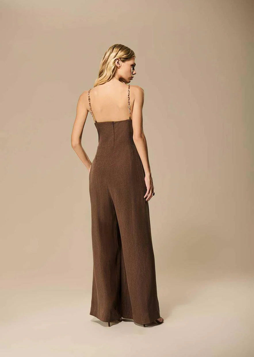 Woman wearing a brown jumpsuit against a beige background