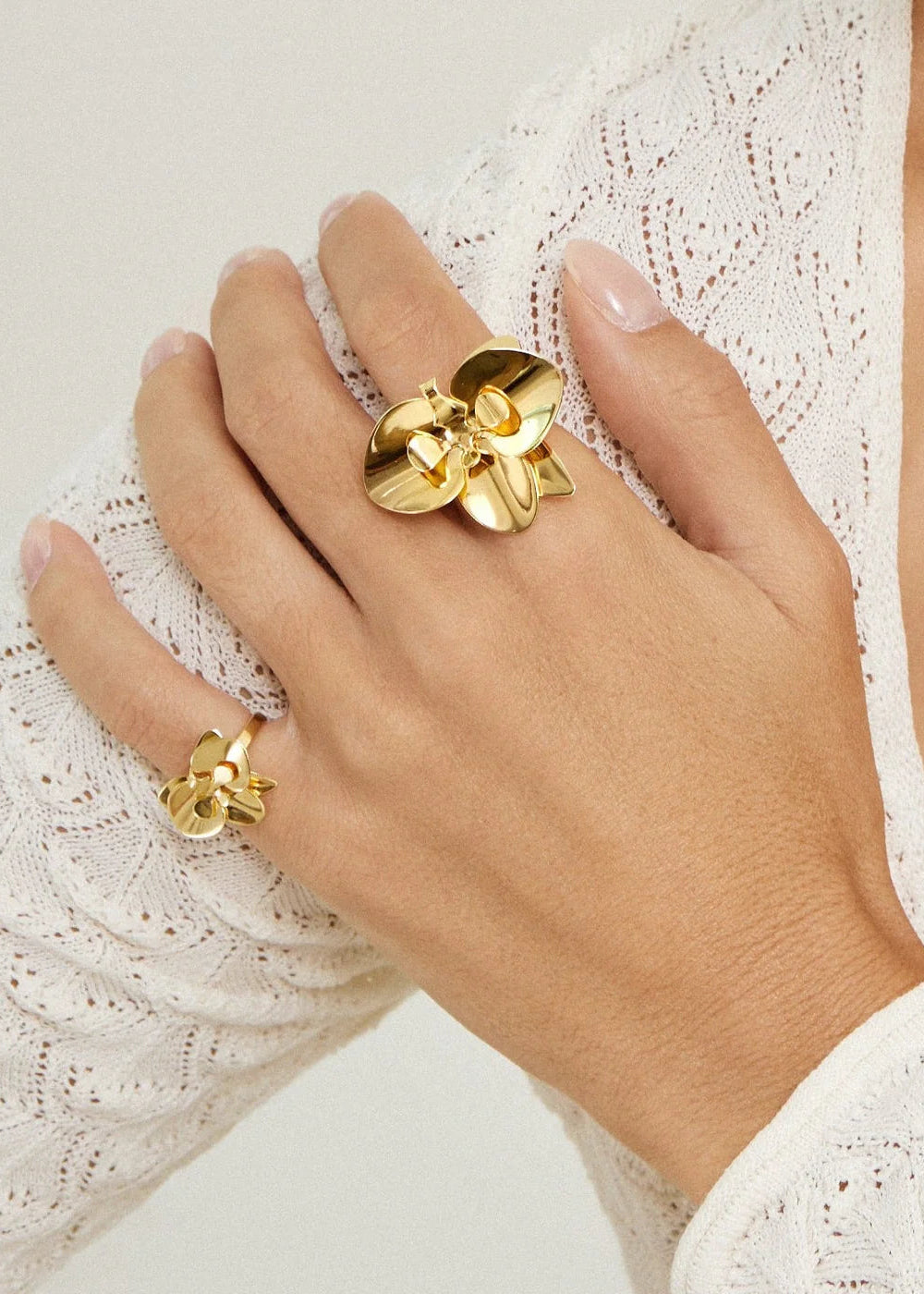 Gold ring on a hand with a white lace background
