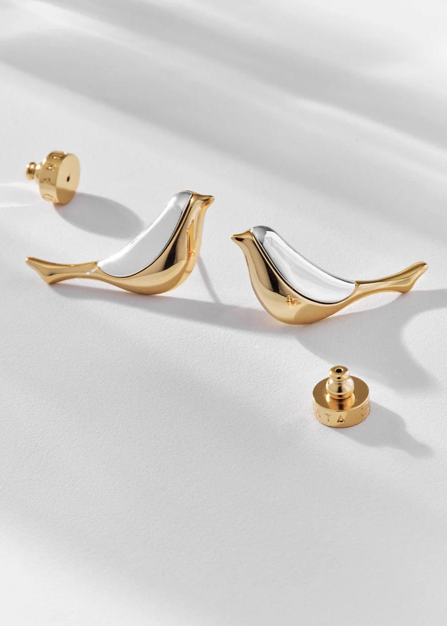 Gold and silver earrings on a white fabric background