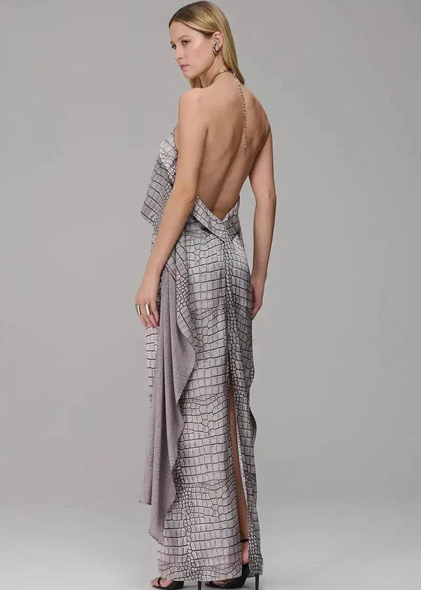 Woman wearing a patterned dress with an open back on a plain background